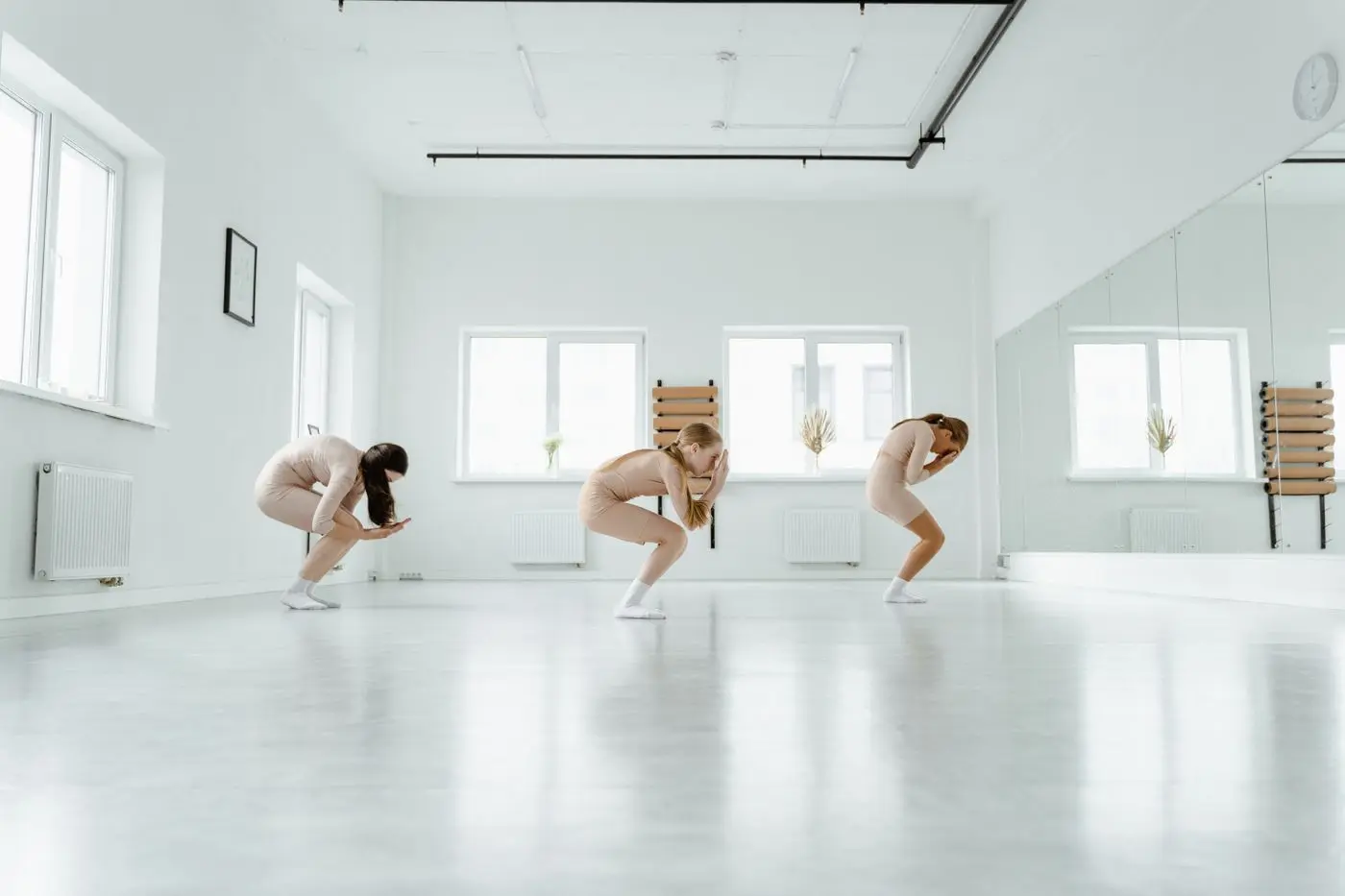 Trois danseuses répétant une chorégraphie contemporaine dans un studio lumineux