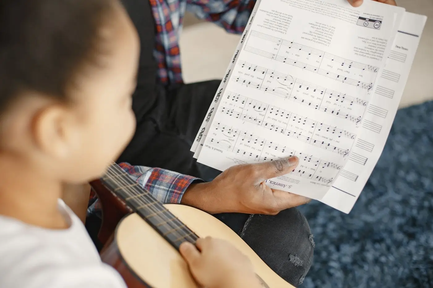 Jeune musicienne apprenant la guitare à partir d’une partition