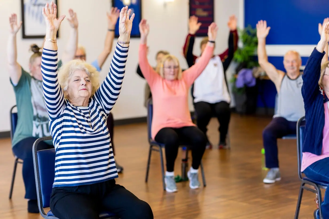 Groupe d’adultes réalisant un exercice guidé de respiration et de mouvement assis sur des chaises